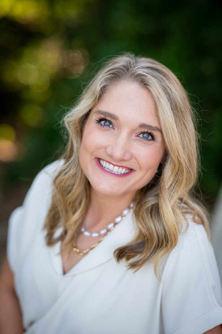 Blonde woman with necklace smiling brightly