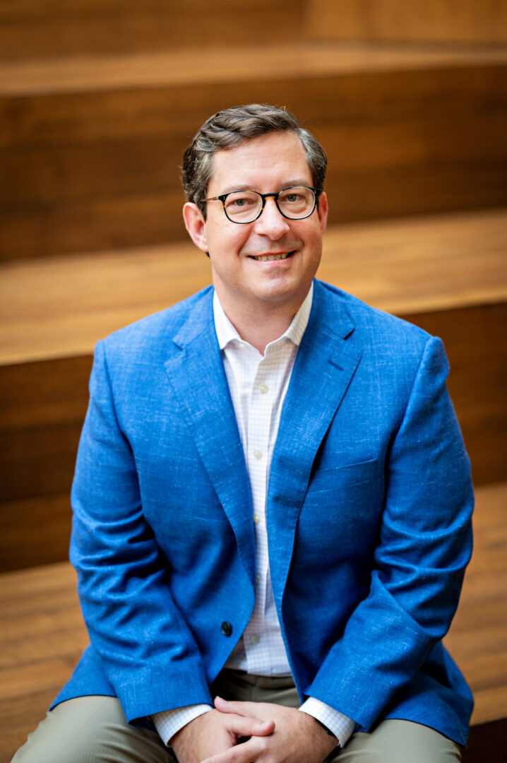 Individual wearing glasses and blue jacket