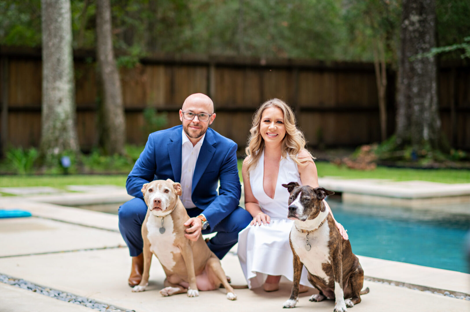 Smiling couple posing outdoors with dogs